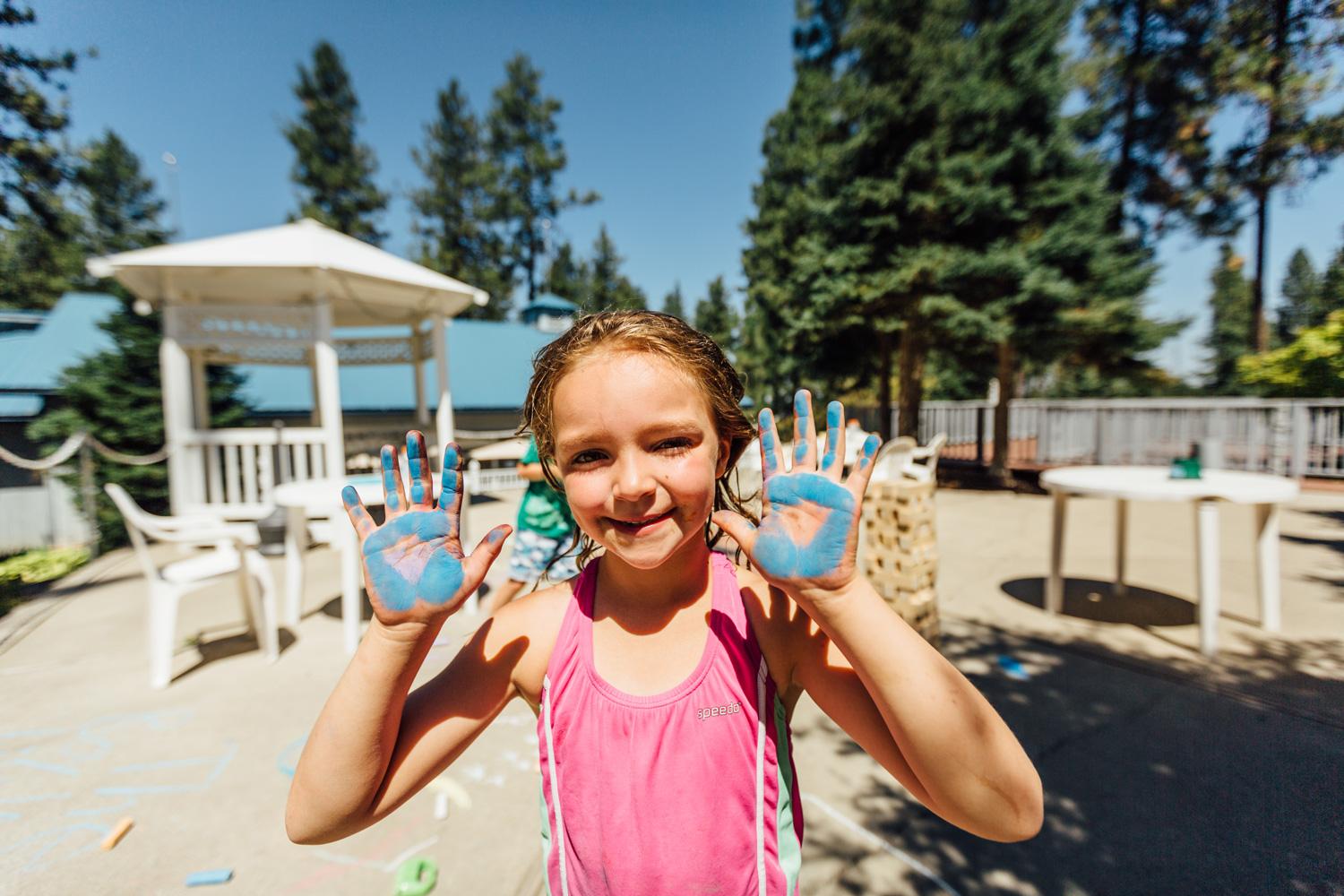 Young girl with blue chalk on her hands