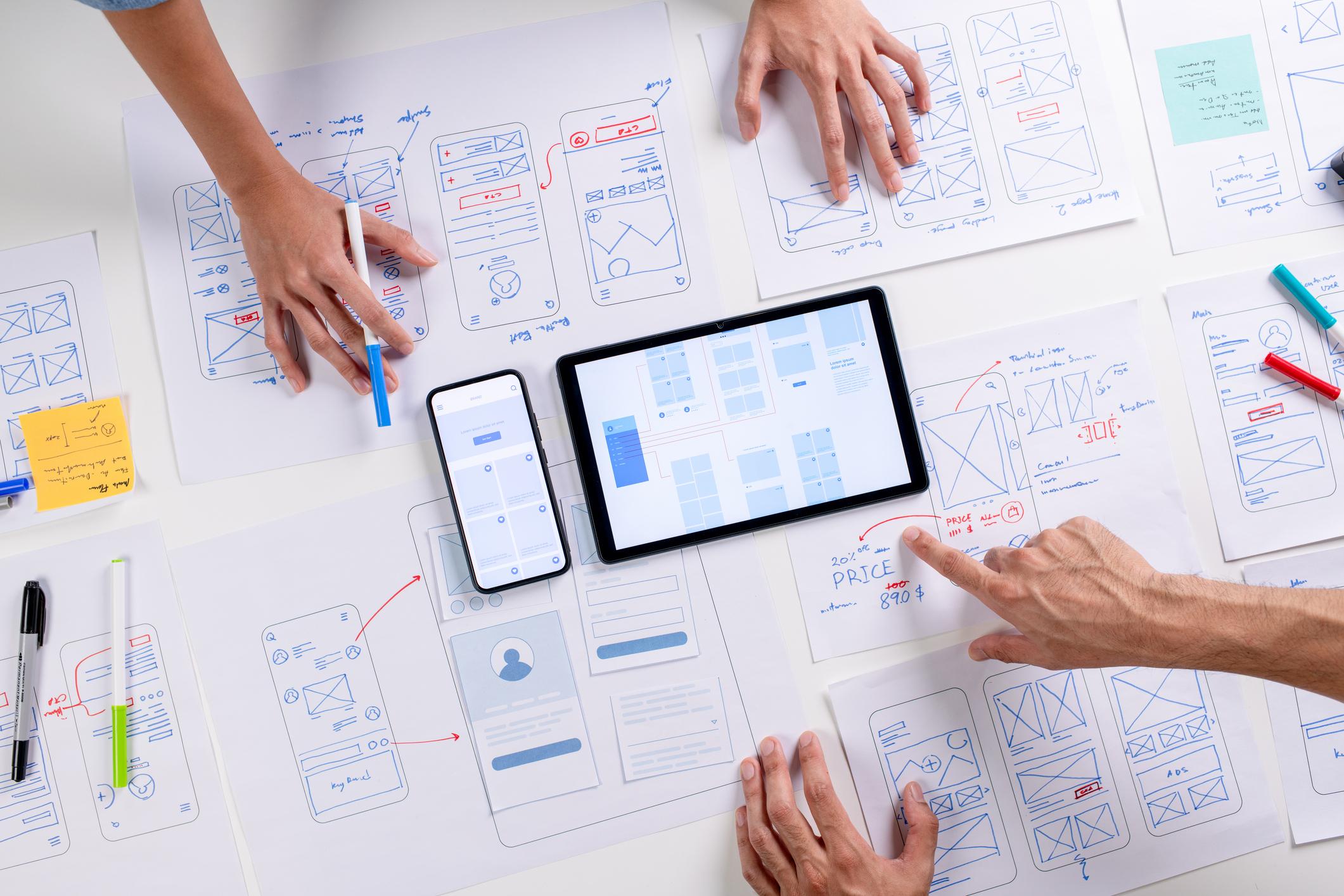 Overhead view of designers planning a website with pieces of paper