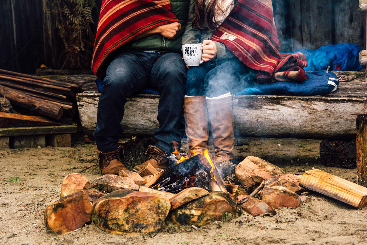 Couple drinking coffee by a fire