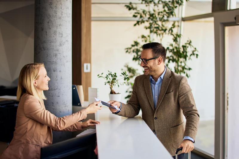 Professional Businessman Requesting Service from Receptionist at an Office Front Desk